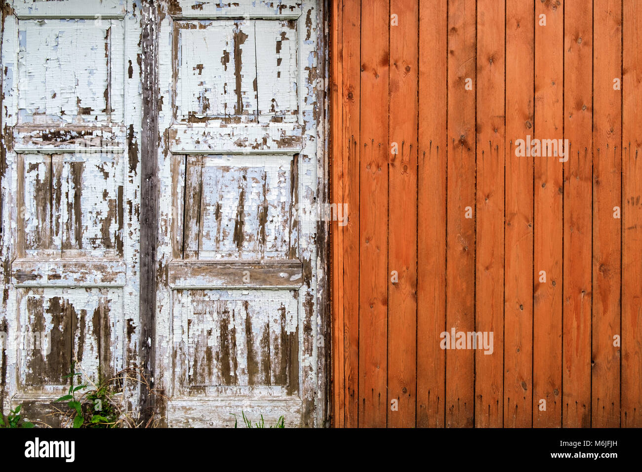 Vecchio muro di legno fatto di pannelli di porte scabro e tavole di legno arancione in campagna. Vista frontale Foto Stock