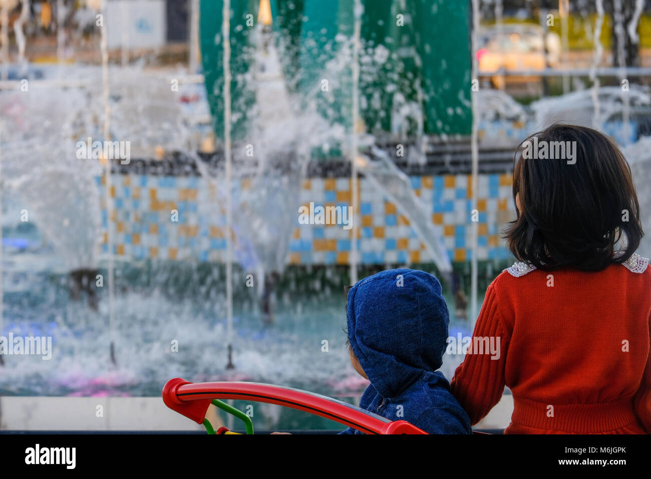 Due asian le piccole bambine in piedi nel Carrello della spesa guardando la fontana nella parte anteriore del Centro Commerciale di Mushrif Foto Stock
