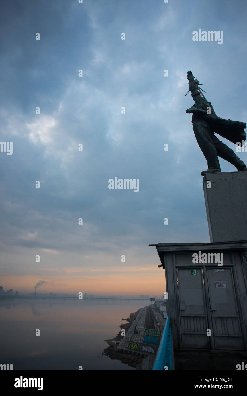 Mattinata nebbiosa. Un monumento nei pressi del ponte della metropolitana, oltre il Dnipro River, Kiev, Ucraina Foto Stock
