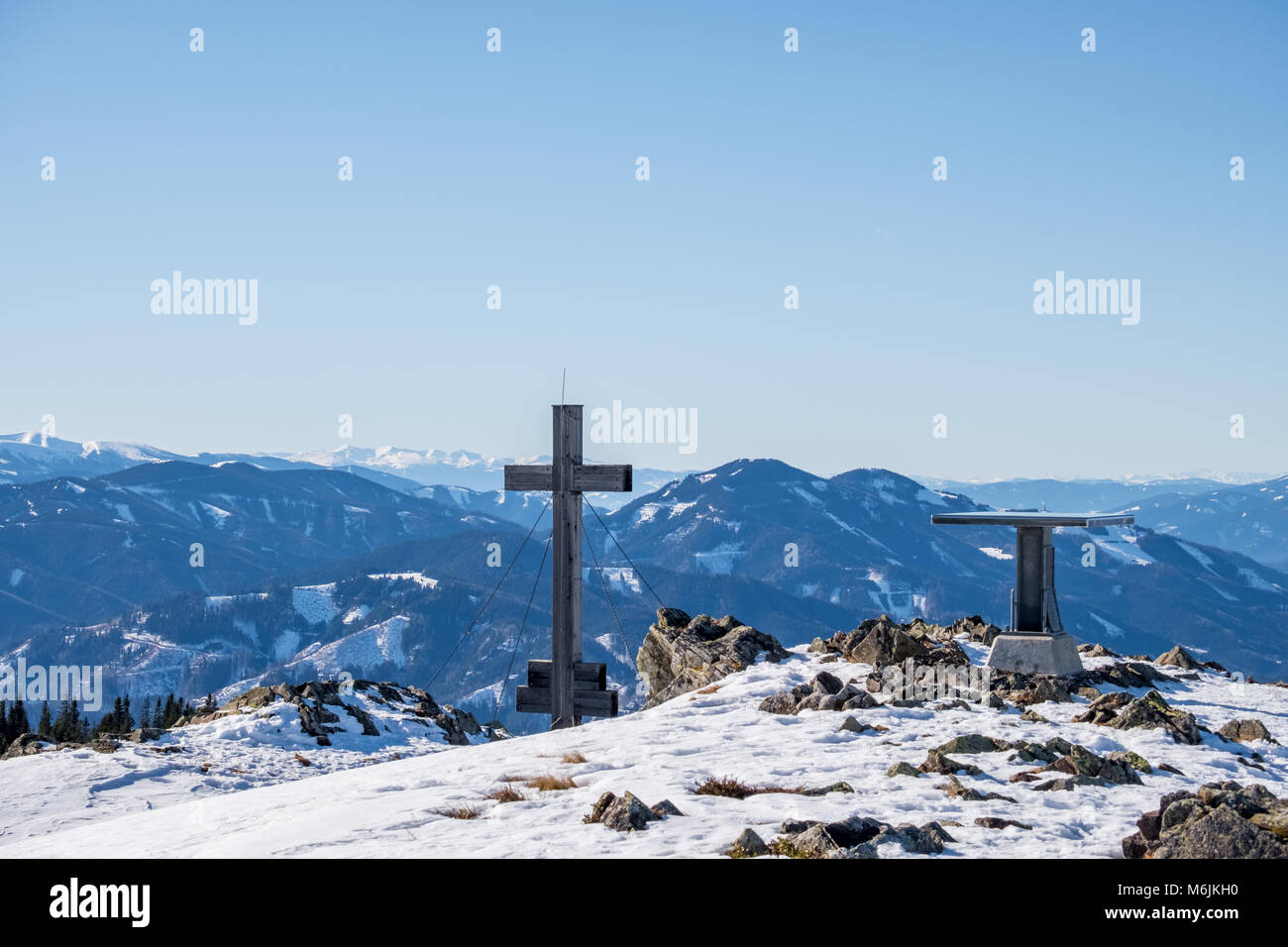 Panoramica paesaggio innevato vista panoramica dalla cima del monte Rennfeld con la croce e la tabella e lontane cime Rosseck e Mugel in inverno Foto Stock