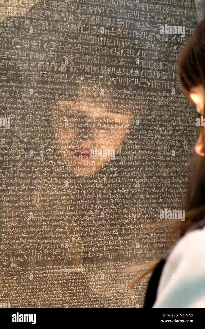 Ragazze volto riflesso come lei tenta di leggere la Rosetta Stone con la scrittura in diverse lingue antiche - messa a fuoco selettiva - nel British Museum a Londra U Foto Stock