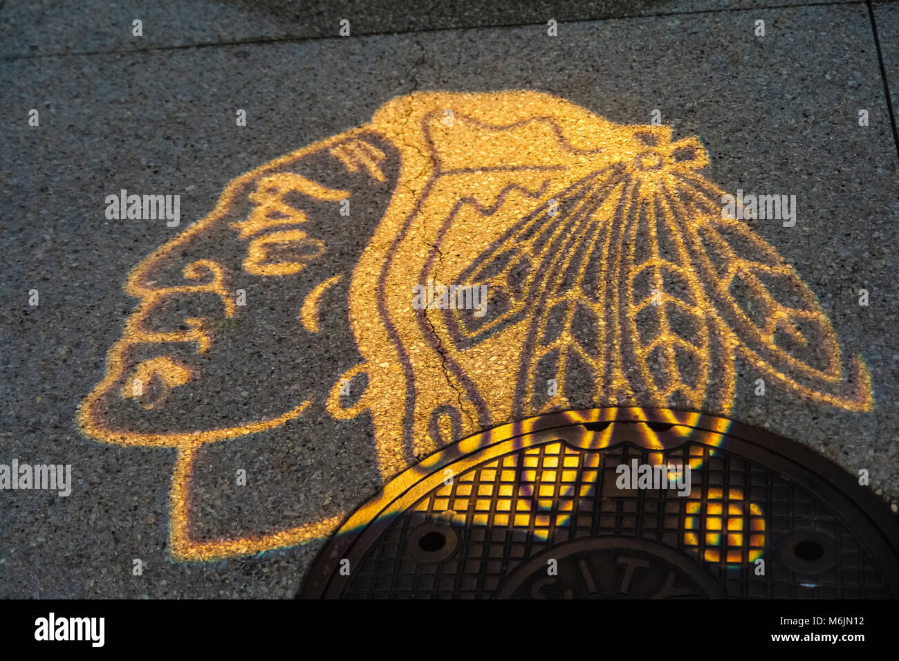Il logo del Chicago squadra di hockey il BlackHawks proiettata su un marciapiede dietro il negozio BlackHawks nel distretto di Loop, Chicago, Illinois. Foto Stock