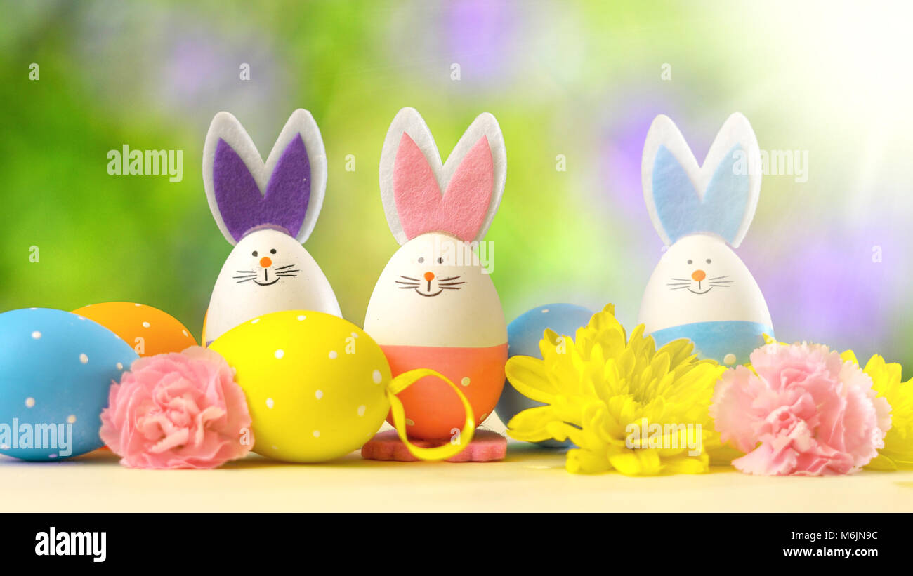 Simpatico coniglietto di pasqua ornamenti e uova di Pasqua sul tavolo bianco contro lo sfondo del giardino con lens flare. Foto Stock