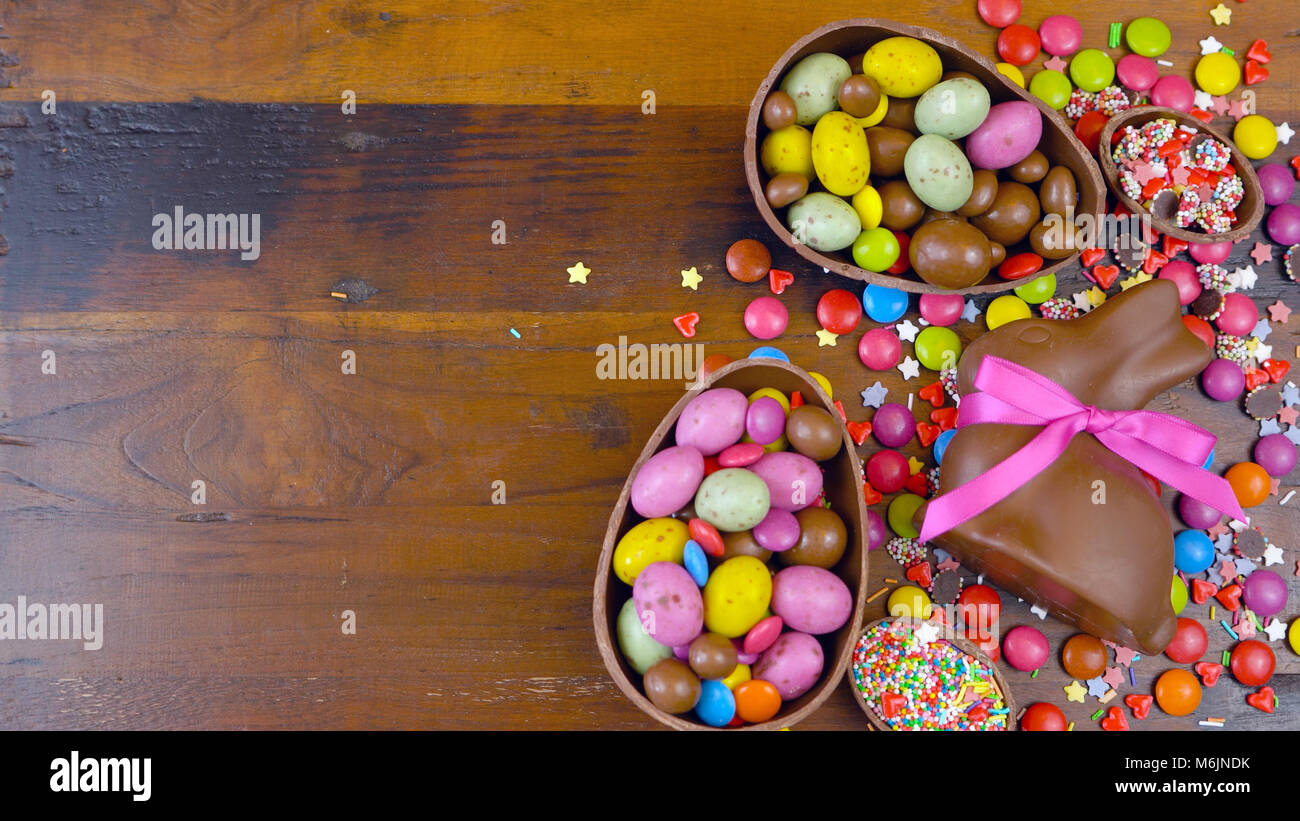 Felice Pasqua in testa con le uova di Pasqua di cioccolata e decorazioni su una tavola di legno sfondo con copia spazio. Foto Stock