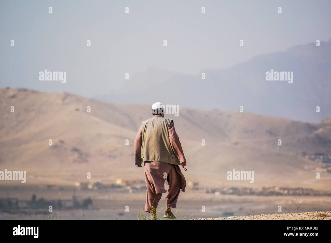 Un uomo afghano camminando in abiti tradizionali o vestito su una collina a Kabul in Afghanistan Foto Stock