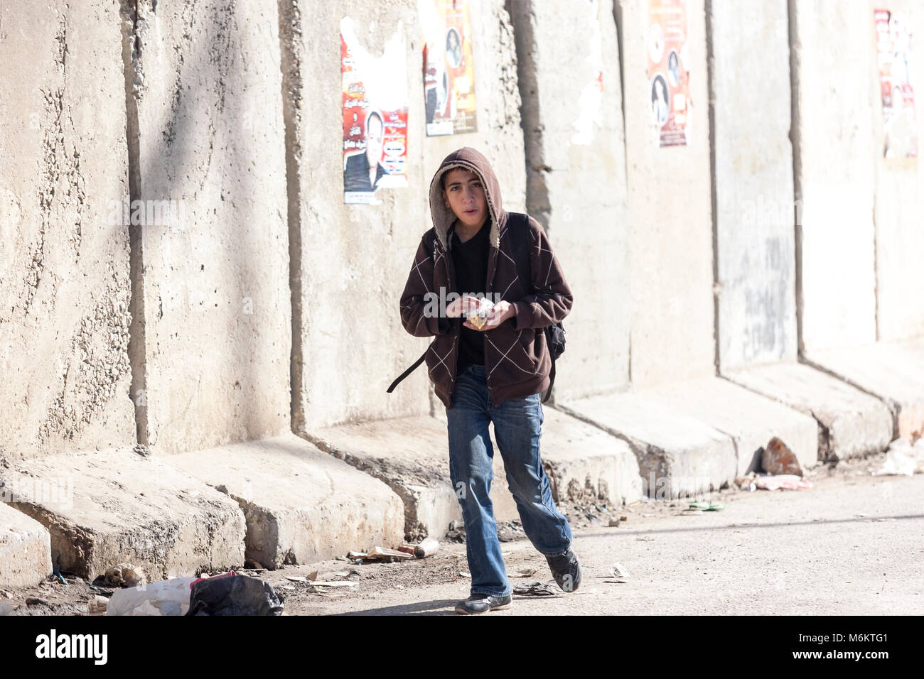 Kalandia, Palestina, 12 Gennaio 2011: il ragazzo è un passaggio di un muro di cemento nei pressi di Kalandia check point costruito da Israele per fermare i palestinesi il pendolarismo in EA Foto Stock