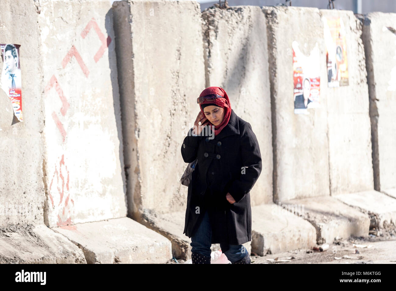 Kalandia, Palestina, Gennaio 12, 2011: una donna è il passaggio di un muro di cemento nei pressi di Kalandia check point costruito da Israele per fermare i palestinesi il pendolarismo in Foto Stock