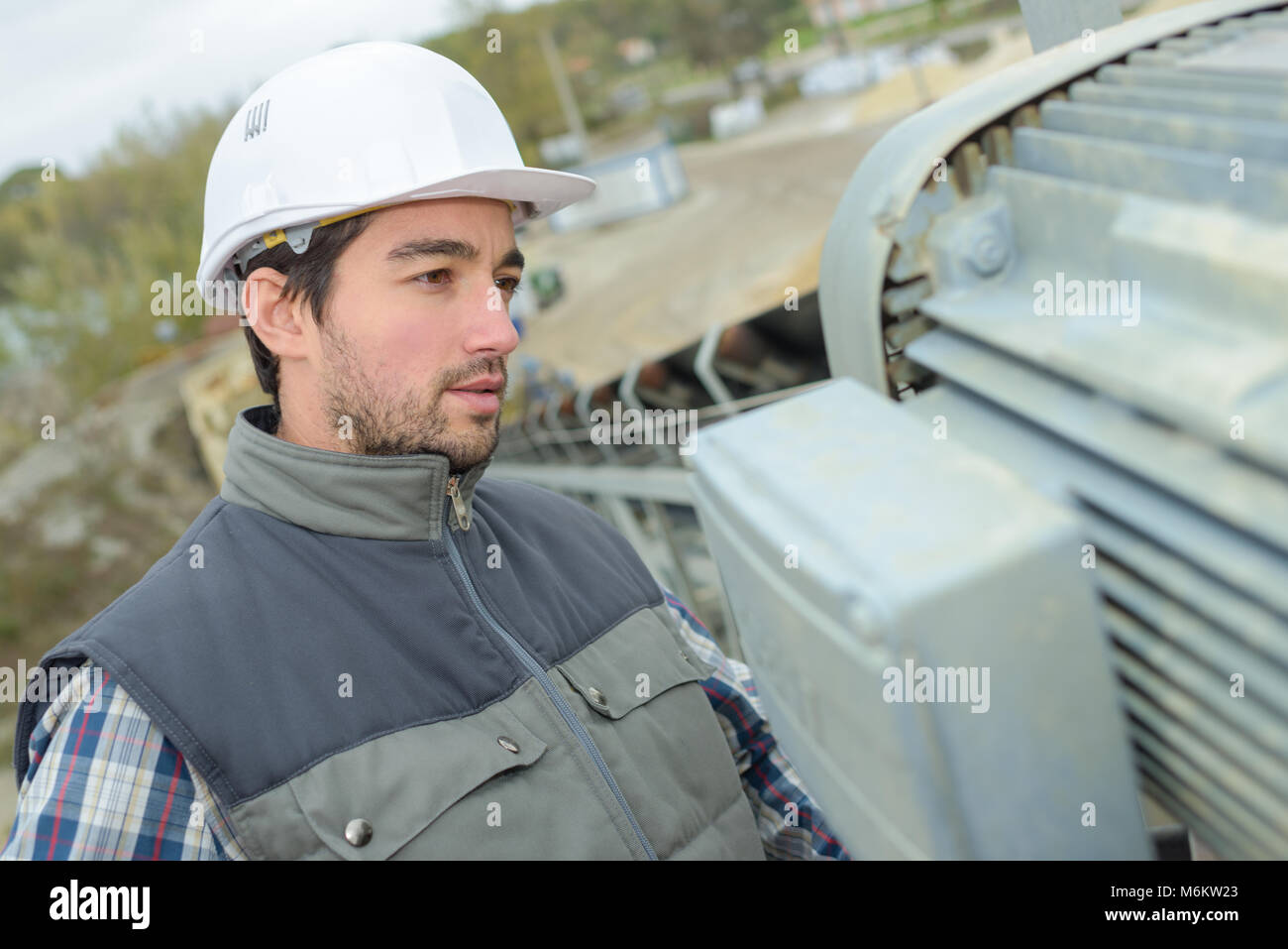 Lavoratore di ispezionare il motore del convogliatore Foto Stock