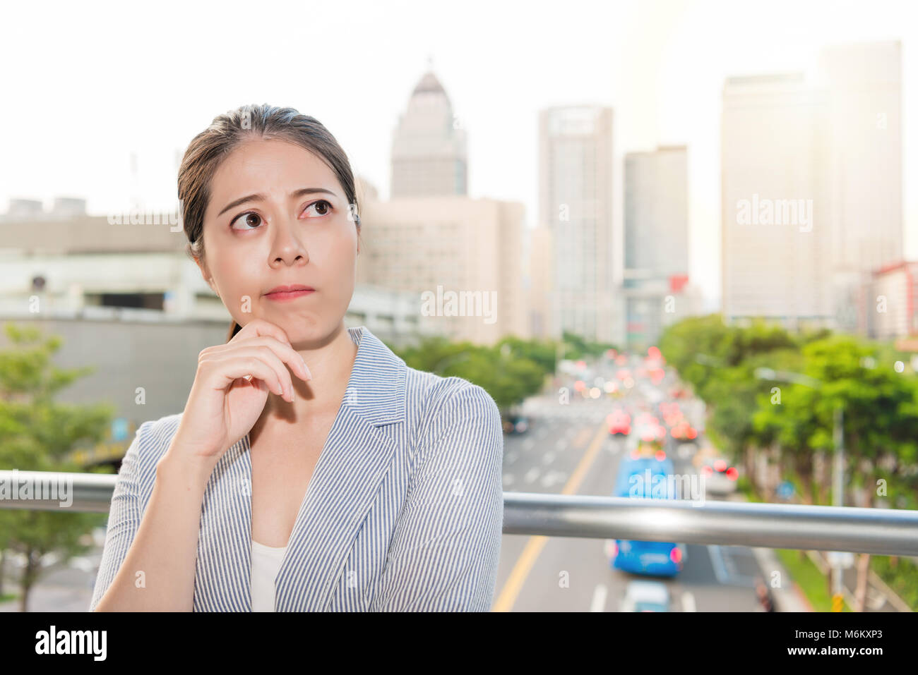 Ufficio di bella donna pensa della soluzione di bad inquinamento atmosferico per i picchi di traffico del tempo. Foto Stock