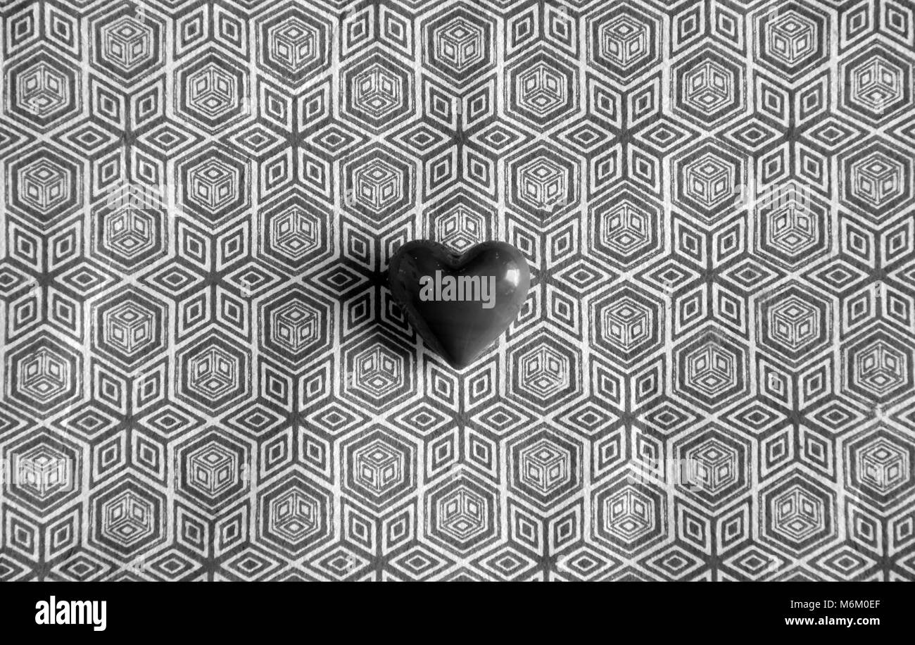 Piccolo rosso amore cuore ciottoli contro uno sfondo semplice Foto Stock