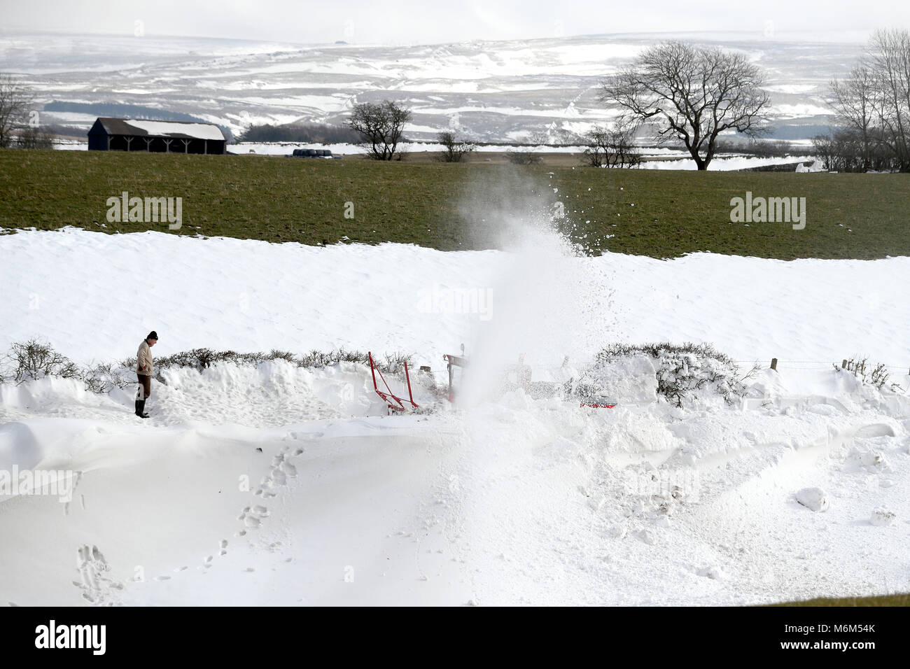 Proprietario di una casa veglia su di uno spalaneve come si libera la strada che conduce ad un piccolo borgo che è stato bloccato dal giovedì al Parkhead nei pressi di Kirkoswald, Cumbria. Foto Stock