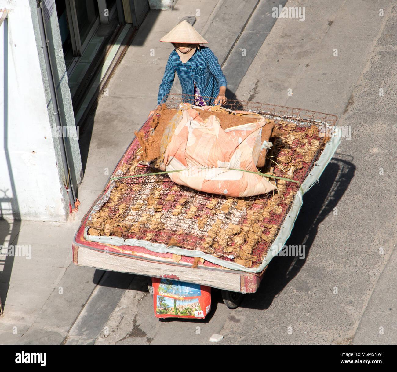 A Saigon, Vietnam, 18 dic. 2017, Vietnamita donna spingendo un carrello con un grande vecchio materasso. La vita sulla strada a Saigon city. Foto Stock