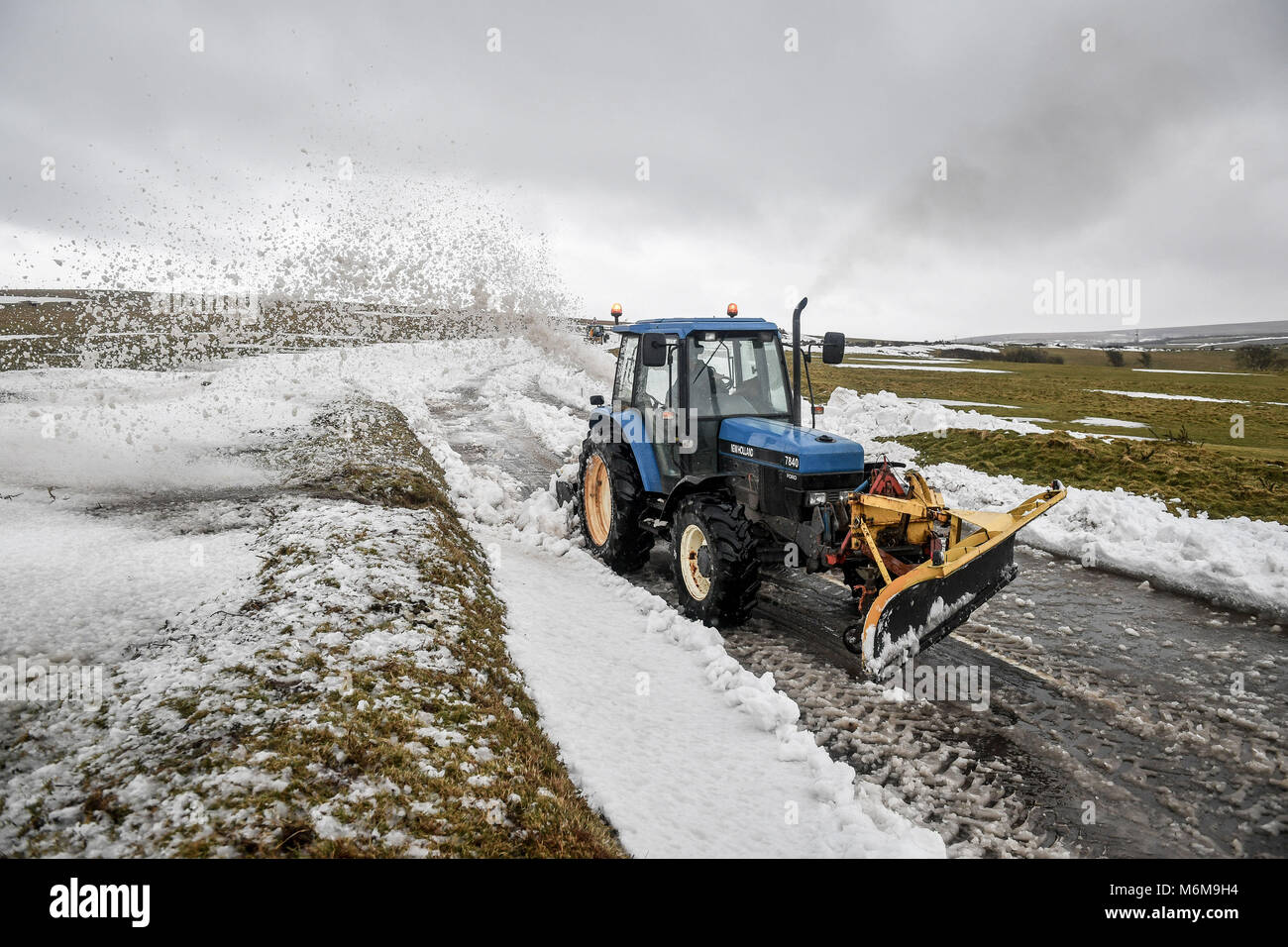 Macchine agricole è utilizzato per cancellare la neve da una sezione della A39 a Porlock Hill, vicino a Lynton, Exmoor, dopo pesanti derive di neve ha interessato la zona e tagliare Lynton Village. Foto Stock