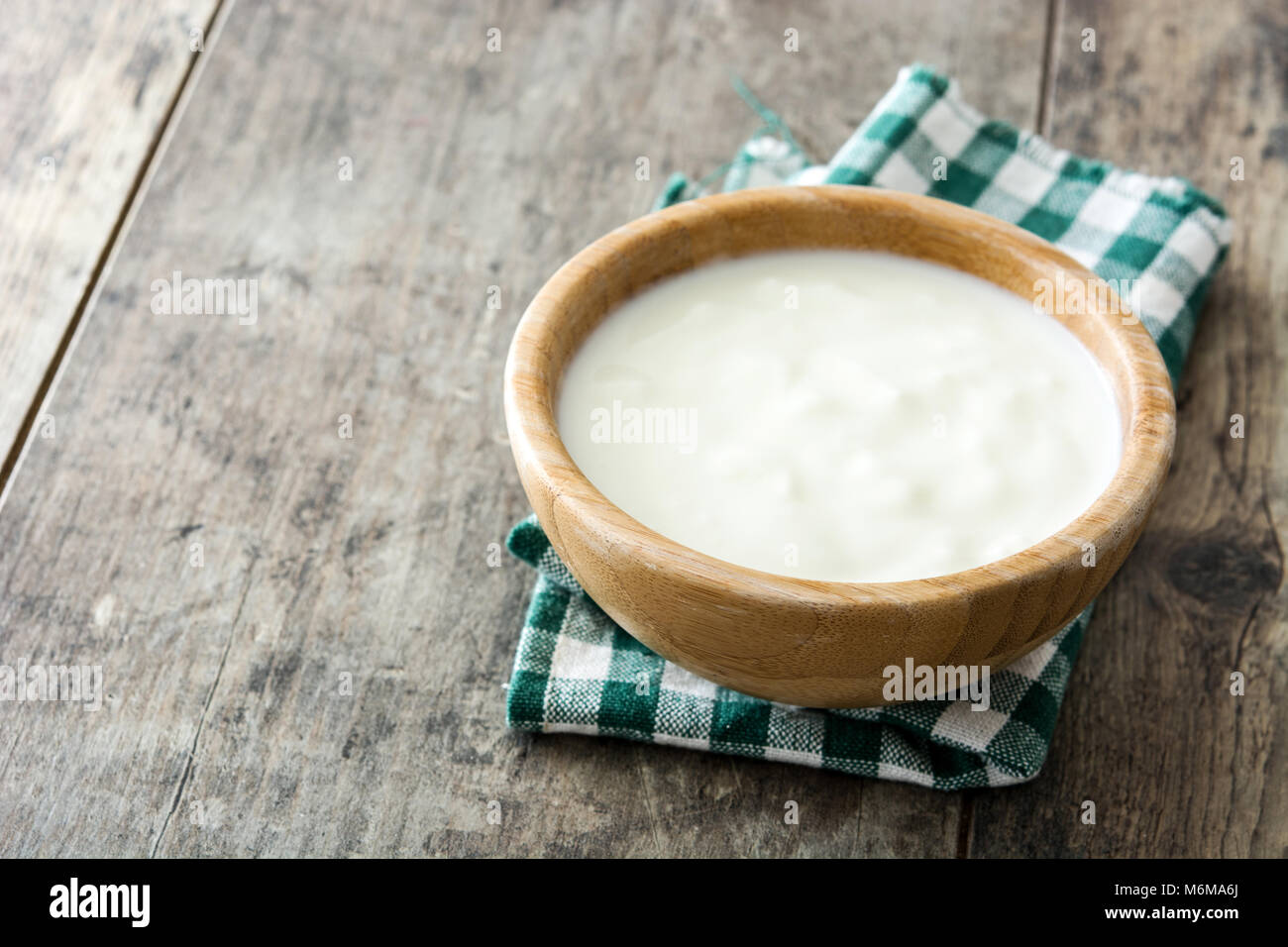 Lo yogurt naturale in ciotola di legno su un tavolo di legno. Foto Stock