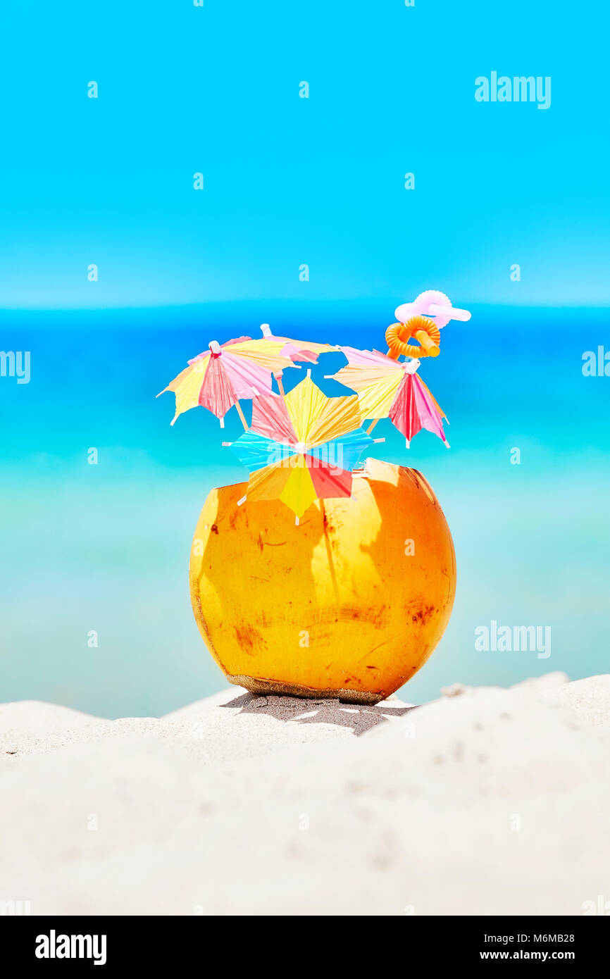 Noce di cocco con ombrelloni colorati e cannucce su una spiaggia, estate vacanza divertente concetto, il fuoco selettivo. Foto Stock