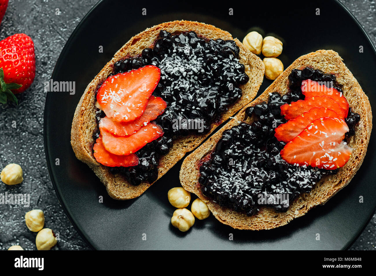 Confettura di mirtilli sul pane con fragole a fette Foto Stock