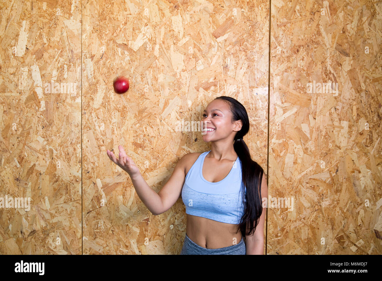 Razza mista donna gettando un Apple in aria Foto Stock