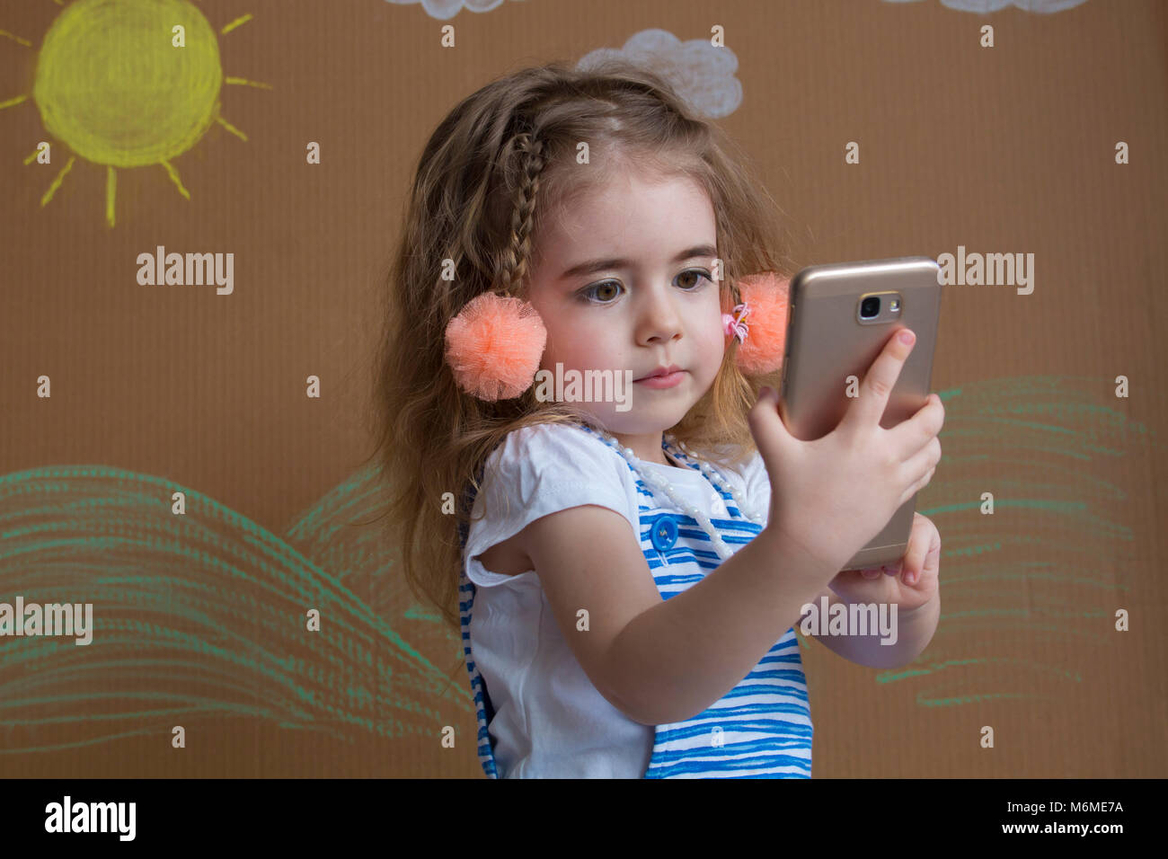 Adorabili poco moderno kid, bionda ragazza toddler giocando con il telefono cellulare. nuove tecnologie digitali nelle mani di un bambino Foto Stock