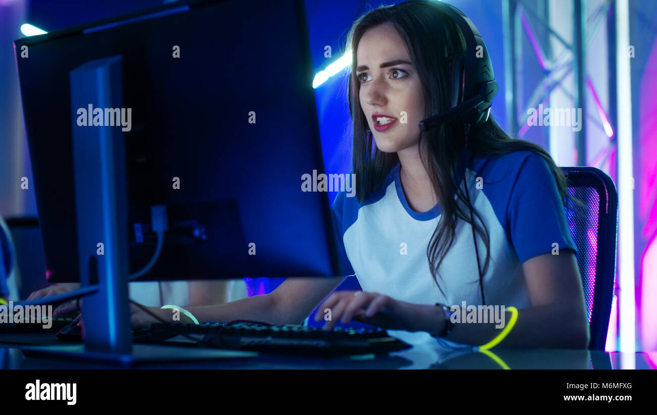 Bella giocatore professionista ragazza e il suo team di partecipare in esporte Cyber Games torneo. Ha le cuffie e fascia colorata sul. Foto Stock