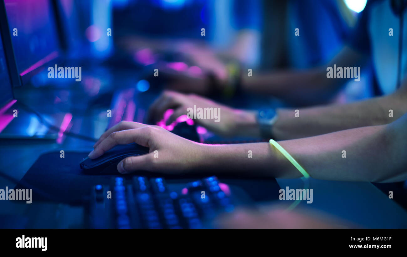 Close-up sulla fila di gamer le mani su una tastiera.jpg attivamente premendo pulsanti, giocando MMO giochi online. Lo sfondo è illuminato con luci al neon. Foto Stock