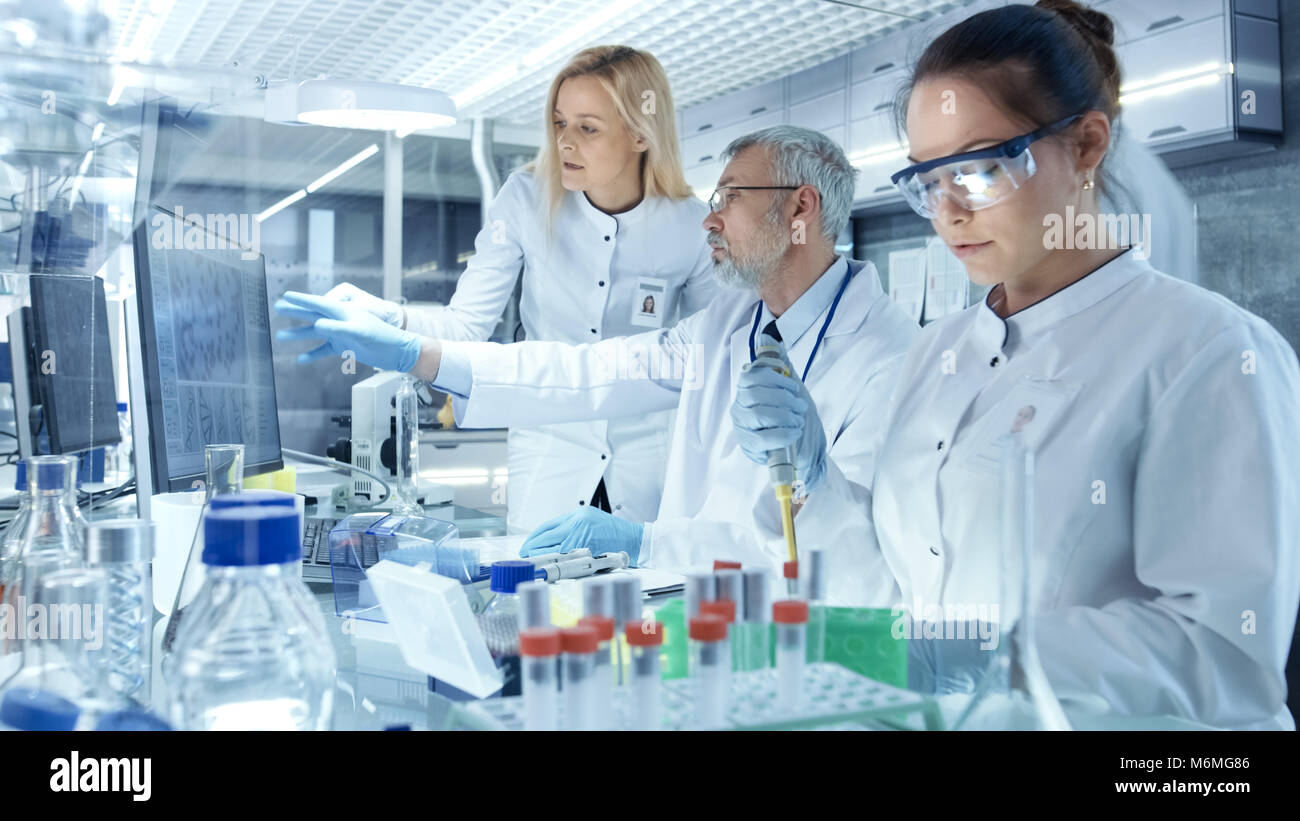 Team di Ricerca gli scienziati che lavorano con Personal Computer, analisi di test di prova di nuova generazione dati di farmaco. Essi lavorano in un moderno laboratorio Foto Stock