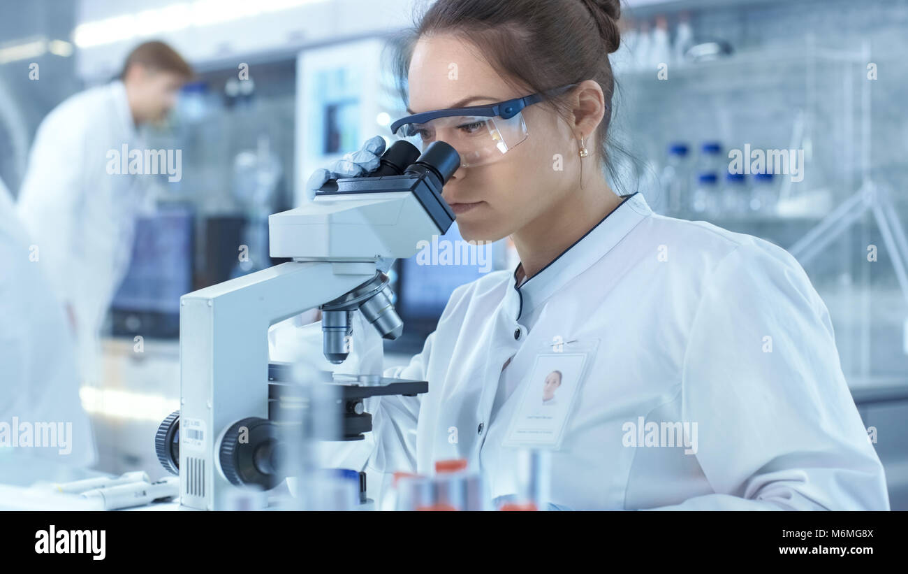 La ricerca medica scienziati guardando i campioni al microscopio. Lavora in un ambiente luminoso e moderno laboratorio. Foto Stock