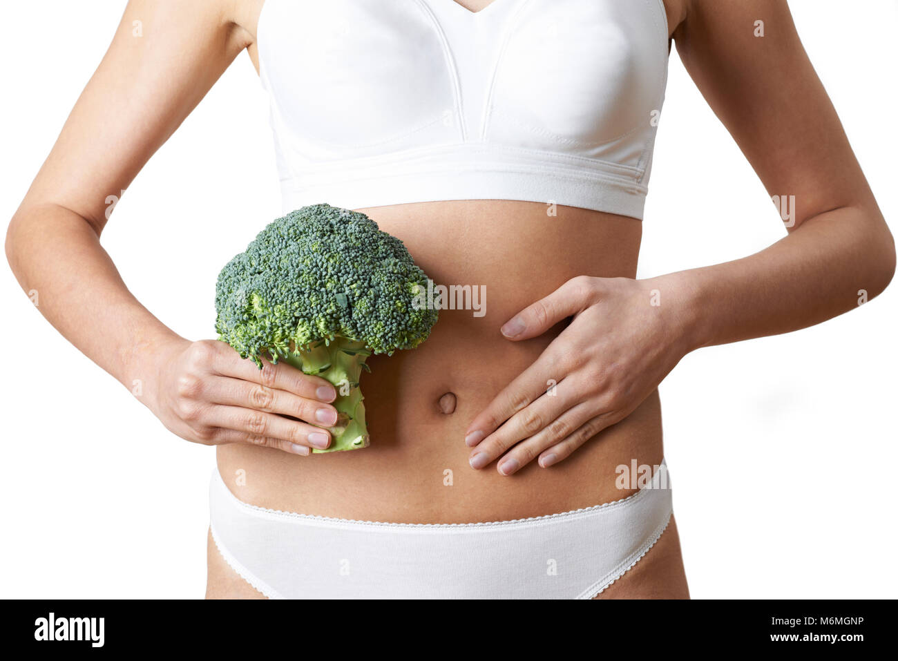 Close up della donna in biancheria intima azienda mazzetto di broccoli e toccando lo stomaco Foto Stock