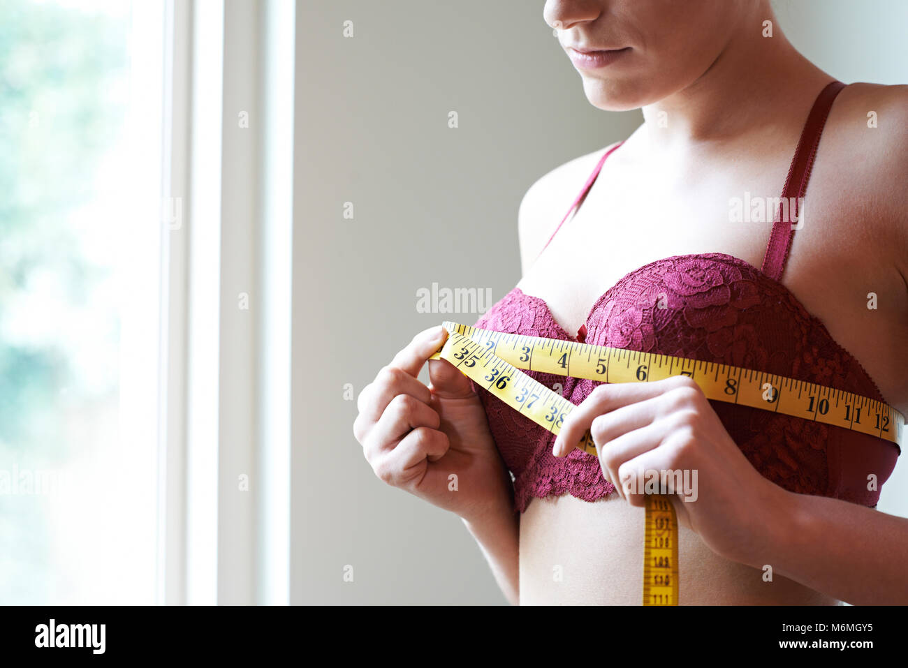 Donna misurando il suo reggiseno dimensioni con nastro di misurazione Foto Stock