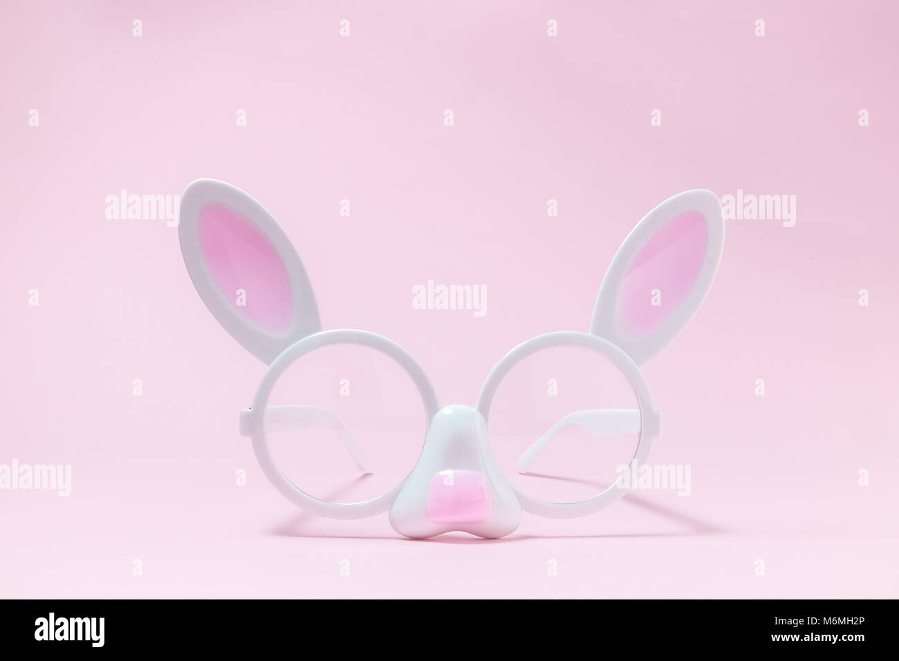 Bunny faccia sagomata su occhiali rosa pastello sullo sfondo la minima nozione. Foto Stock