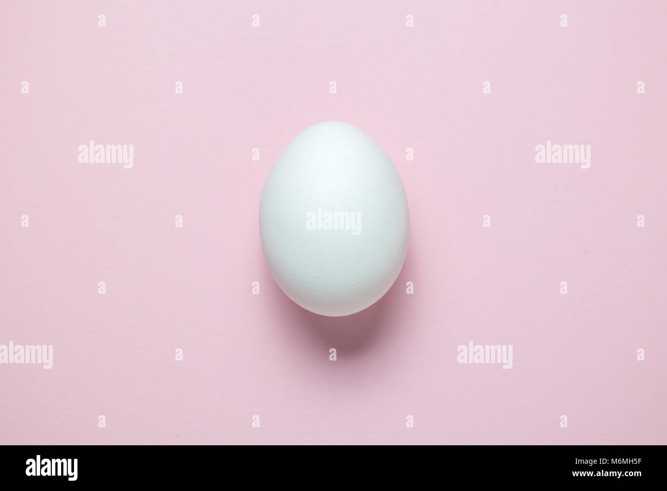 Elevato angolo di visione isolate di uovo sulla pianura pastello rosa sfondo colorato. La minima nozione. Foto Stock