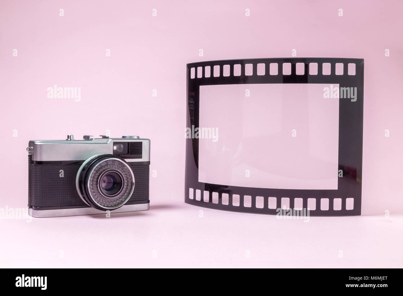 Retro Vintage fotocamera e fotogrammi vuoti nella pellicola fotografica forma contro pastello sfondo rosa la minima nozione. Foto Stock