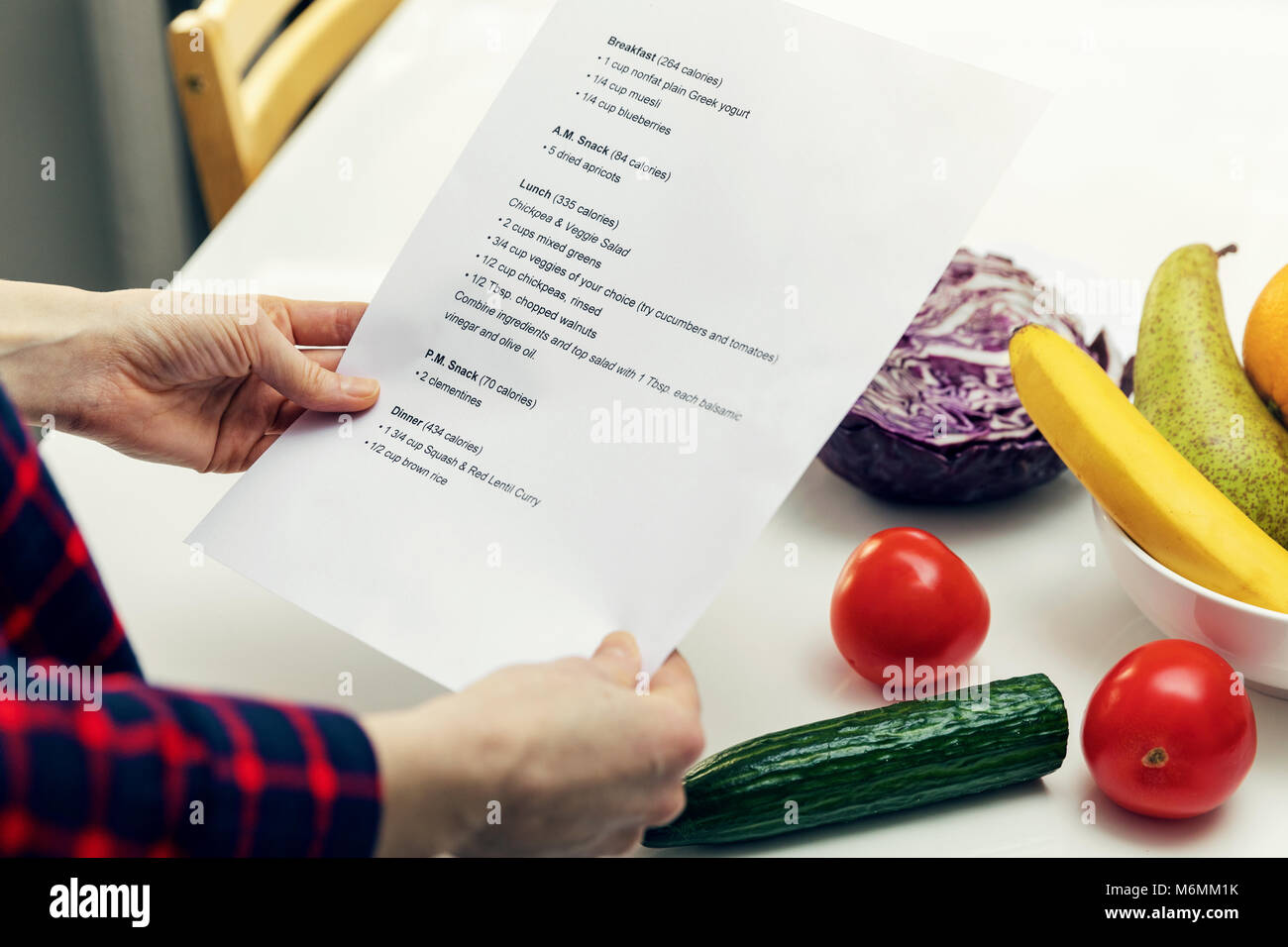 Donna che guarda la dieta bilanciata piano e pronto a cucinare nella cucina di casa Foto Stock