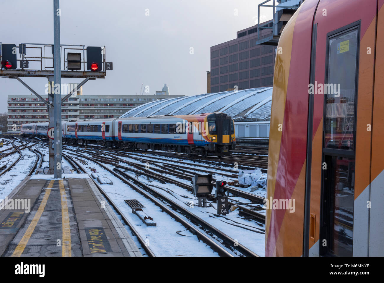 Treni pendolari facendo la loro strada attraverso la neve e il ghiaccio alla Stazione Waterloo di Londra piattaforme durante inverno meteo causando il trasporto pubblico ritardi. Foto Stock