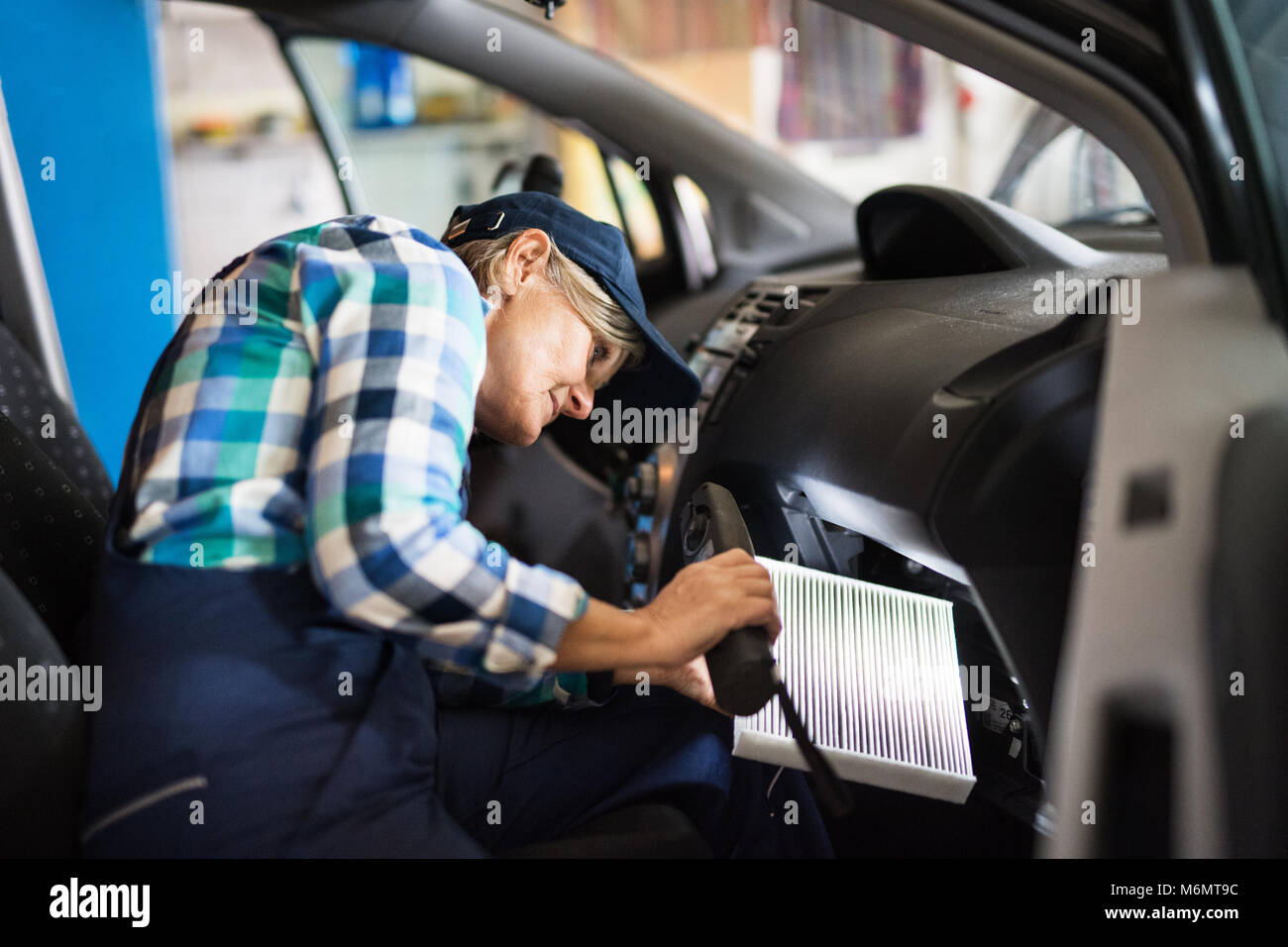 Senior meccanico femmina la riparazione di un auto in un garage. Foto Stock