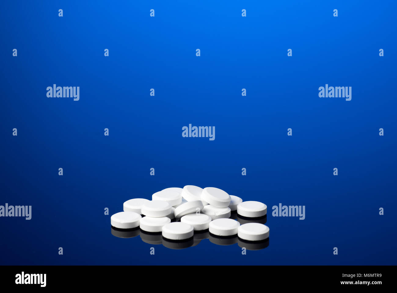 Pila di pillole di bianco. Medical isolati su Cancella sfondo blu Foto Stock