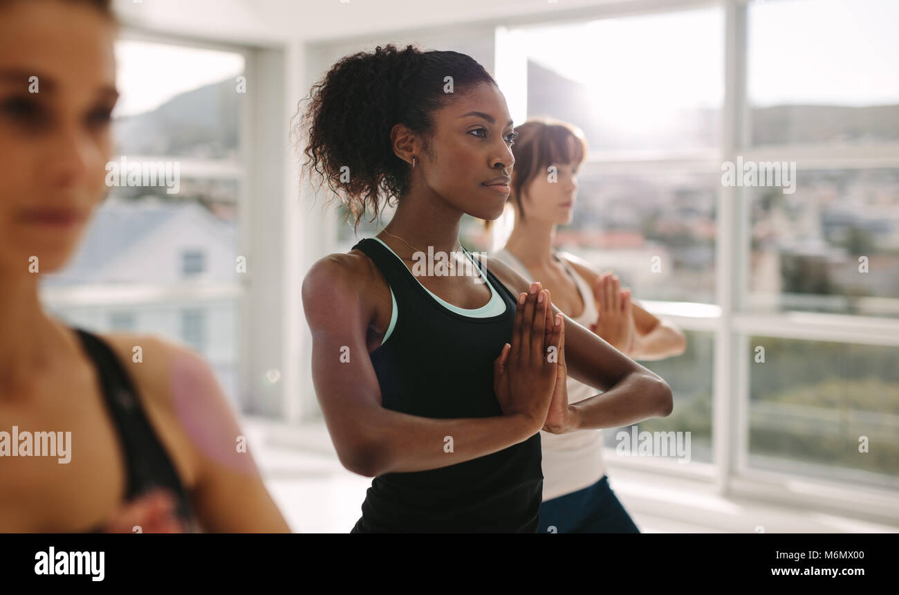 Le donne di stiramento e le pratiche yoga in classe. Sani di sesso femminile a praticare lo yoga allenamento nel centro fitness. In piedi con le mani giunte. Foto Stock