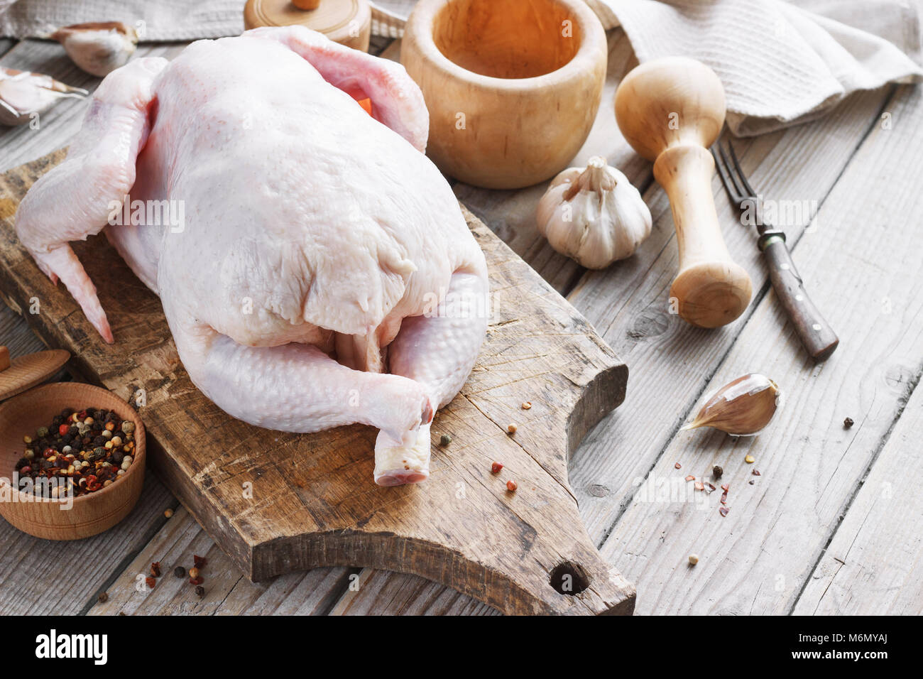 Carcassa di pollo su un sfondo di legno con spezie, cucina in cucina, stile rustico Foto Stock