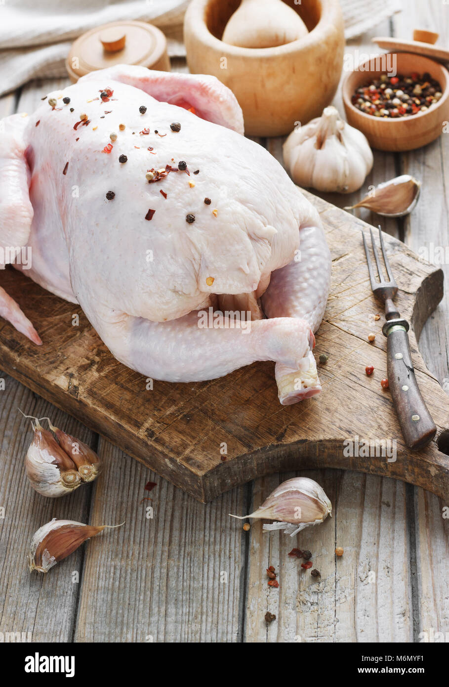 Carcassa di pollo su un sfondo di legno con spezie, cucina in cucina, stile rustico Foto Stock