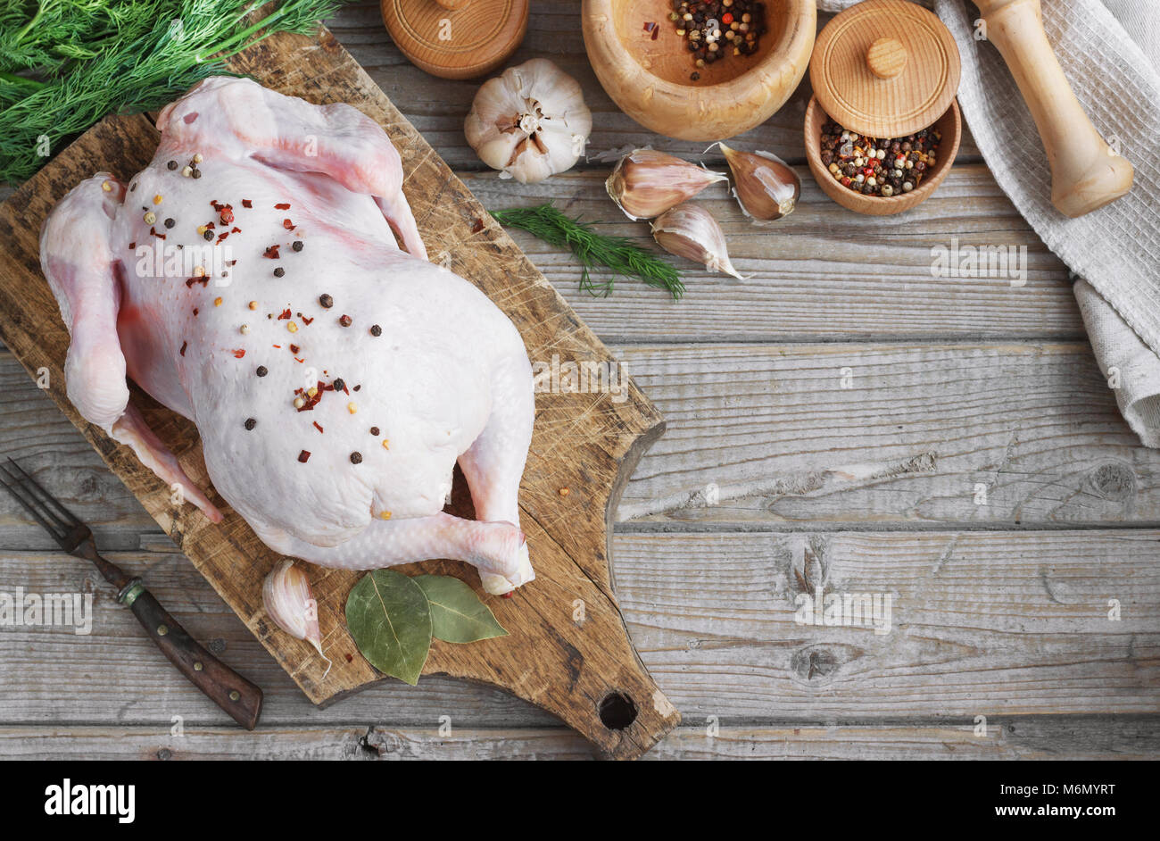 Carcassa di pollo su un sfondo di legno con spezie, cucina in cucina, stile rustico Foto Stock