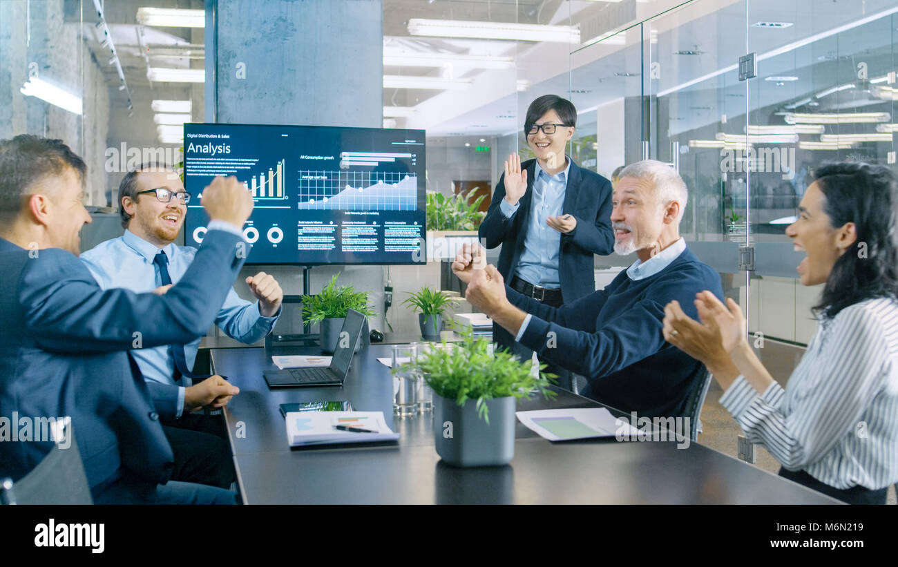 Imprenditore asiatico fornisce report/ Presentazione ai suoi partner commerciali a tutti allegria e applaudire e dare alta cinque approva il suo progetto. Foto Stock