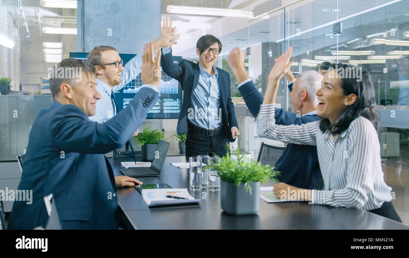 Imprenditore asiatico fornisce report/ Presentazione ai suoi partner commerciali a tutti allegria e applaudire e dare alta cinque approva il suo progetto. Foto Stock