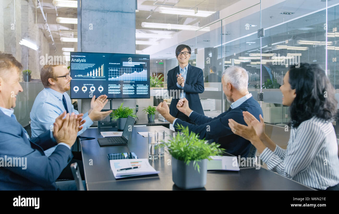 Imprenditore asiatico fornisce report/ Presentazione ai suoi partner commerciali a tutti allegria e applaudire e dare alta cinque approva il suo progetto. Foto Stock