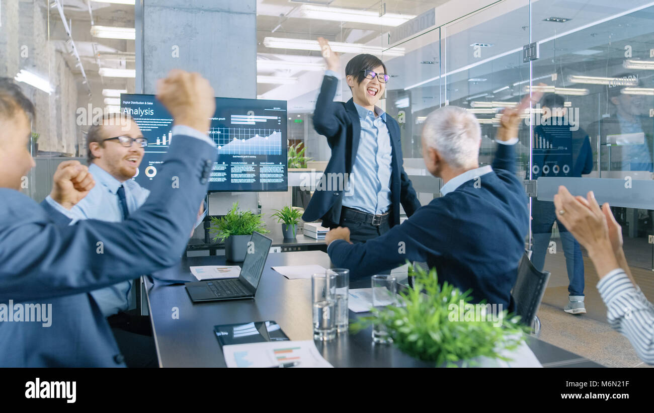 Imprenditore asiatico fornisce report/ Presentazione ai suoi partner commerciali a tutti allegria e applaudire e dare alta cinque approva il suo progetto. Foto Stock