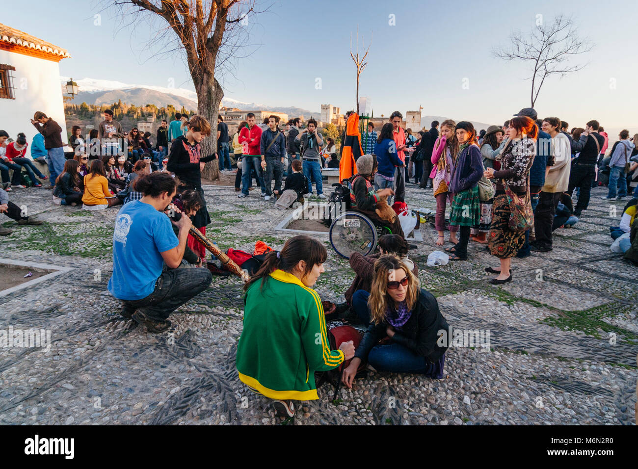 Granada, Andalusia, Spagna. Una folla di turisti e giovani locali raccoglie al tramonto in San Nicolas lookout rivolta verso il palazzo di Alhambra e fort Foto Stock