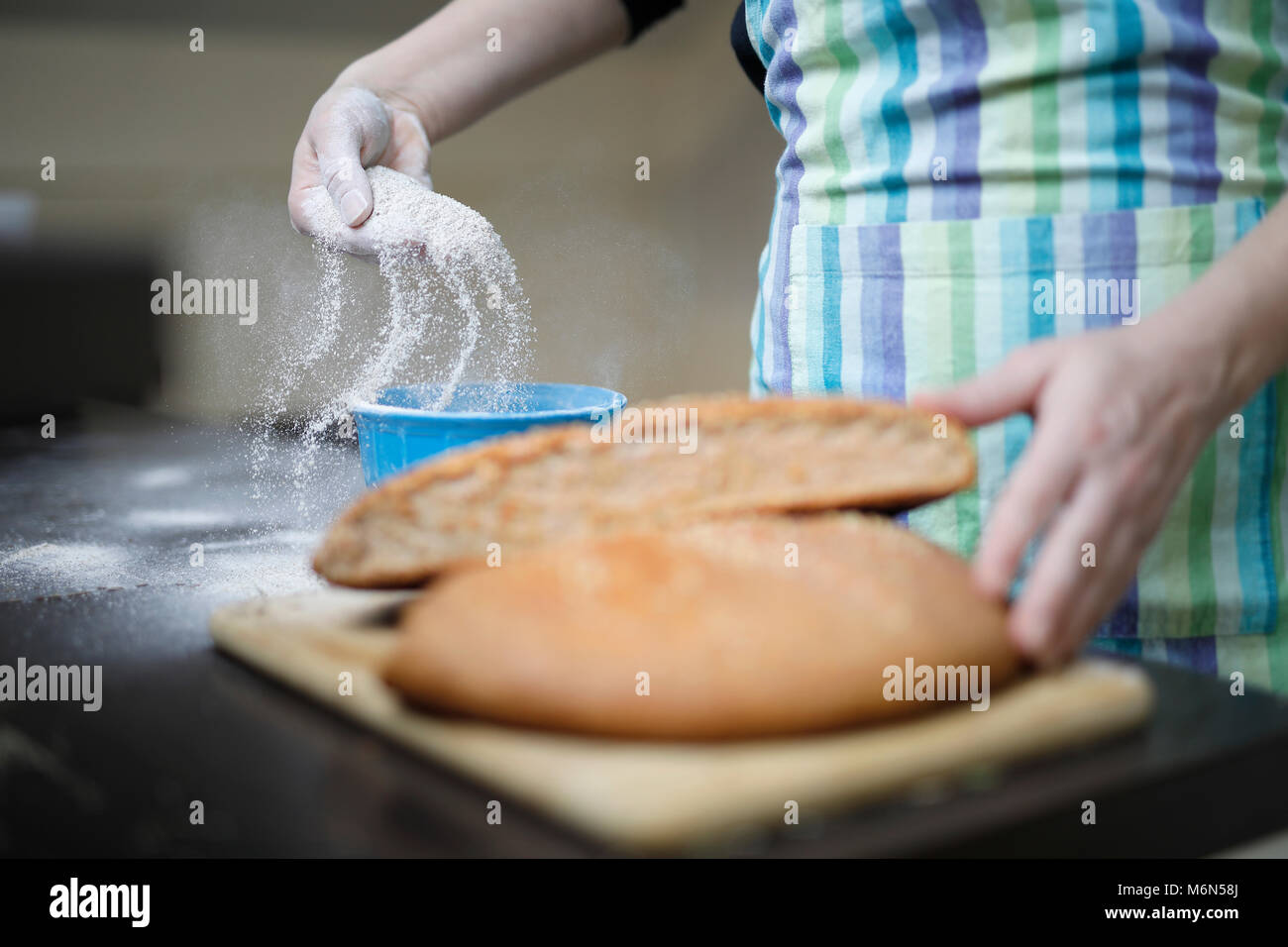 Fatto in casa pane integrale su un tavolo di legno. Donna diffondendo la farina in una ciotola. Foto Stock