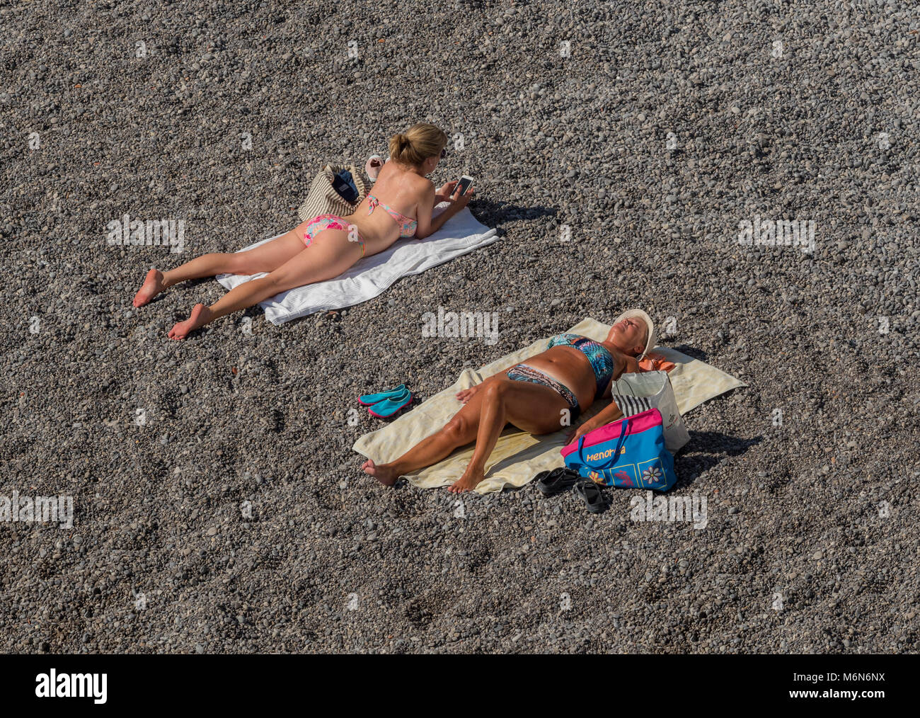 Giovane donna e donna vecchia a prendere il sole sulla spiaggia Foto Stock