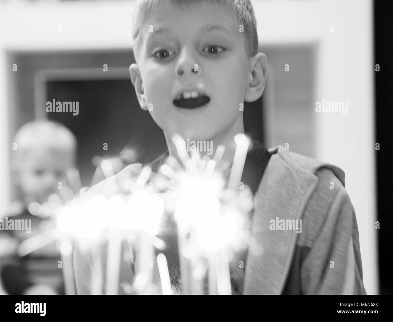 Il 10-anno-vecchio ragazzo caucasico soffiando le candeline sulla torta Foto Stock
