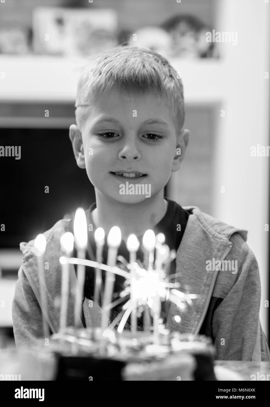 Il 10-anno-vecchio ragazzo caucasico soffiando le candeline sulla torta Foto Stock