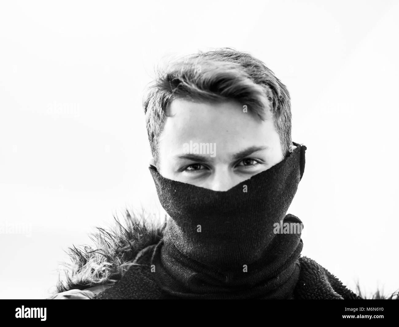 Un giovane uomo caucasico coperto il fondo del suo volto con una sciarpa Foto Stock