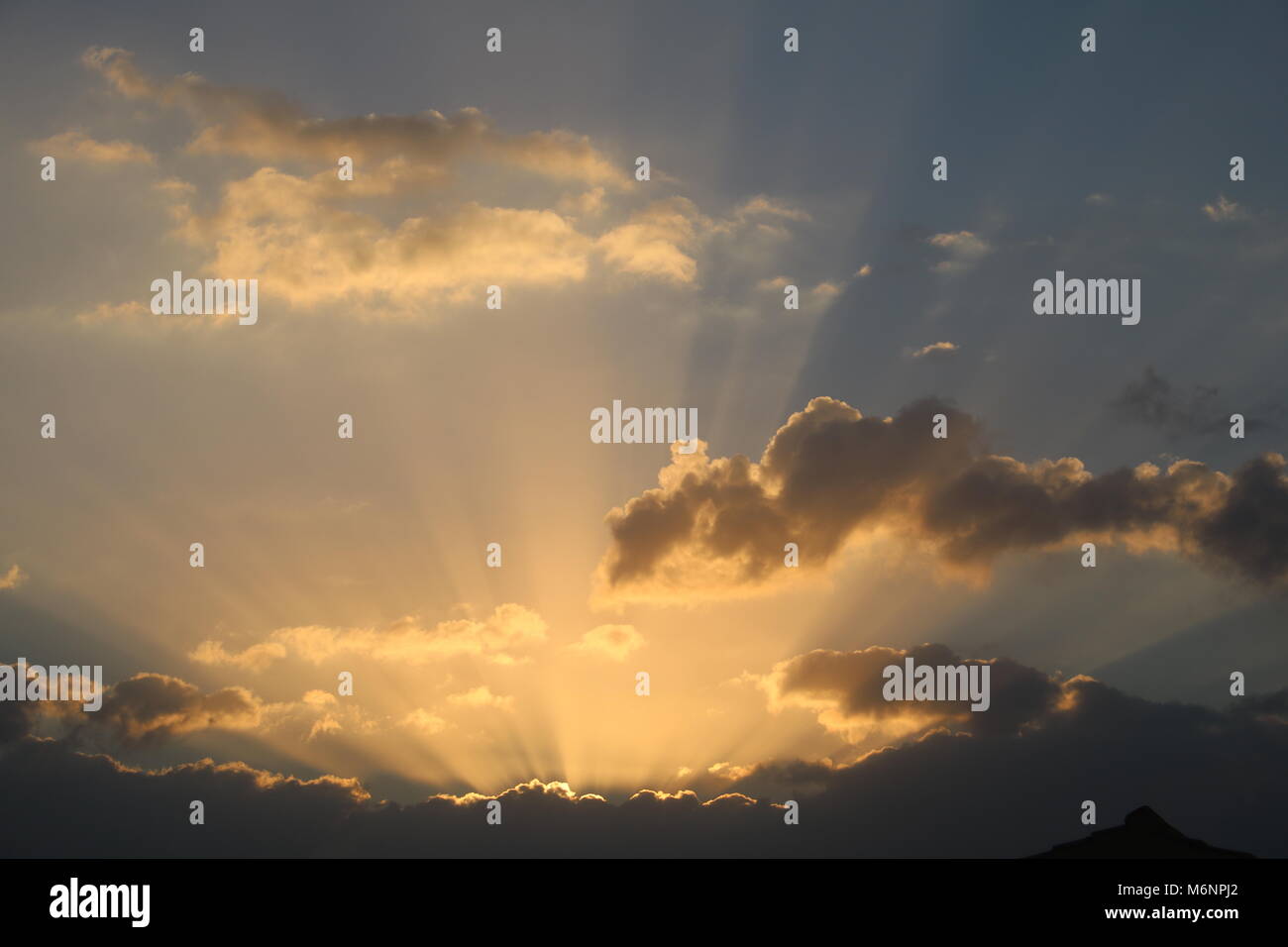 Raggi dorati di mattina presto sunrise scoppio di luce attraverso le nuvole Foto Stock